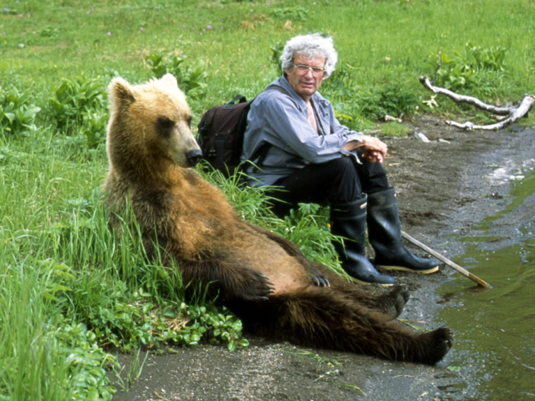 Charlie Russell sitting next to a grizzly bear in Kamchatka. Photo by Maureen Enns Studios Ltd